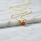 Gold Reindeer Antler Necklace resting on a cool, marbled white and grey background, highlighting its texture and quality.