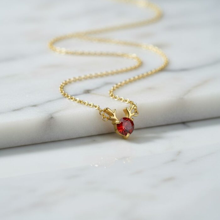 Gold Reindeer Antler Necklace resting on a cool, marbled white and grey background, highlighting its texture and quality.